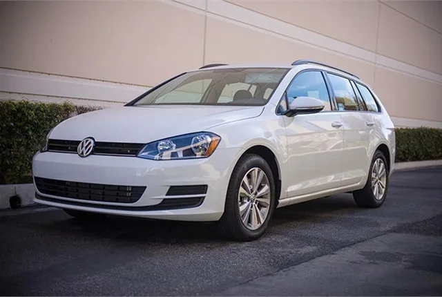 A white 2017 Volkswagen Golf SportWagen 4Motion sits on a road in front of a building.