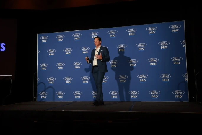 Matt Atkenson of Ford Pro presents on stage in front of a Ford Pro branded backdrop at Work Truck Week while discussing medium-duty truck fleet solutions.