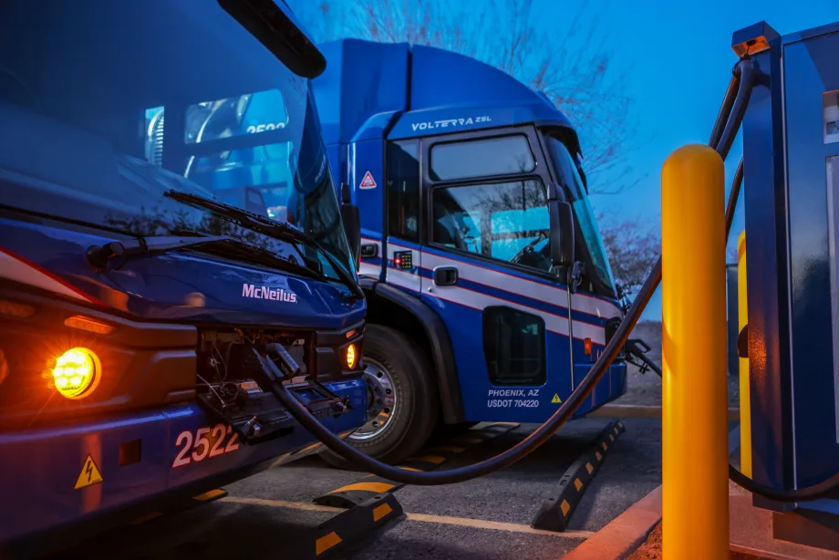 An electric truck is hooked upat a depot at night