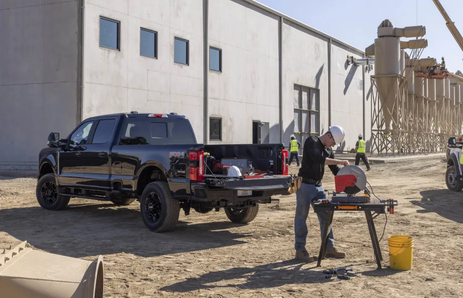 A man is seen using a saw powered by a black 2024 Ford F-250 XL STX Appearance Package.