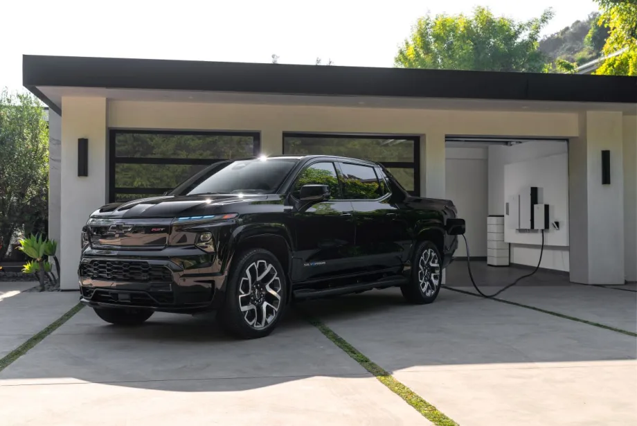 Pickup truck sits outside luxury home's garage getting charged.