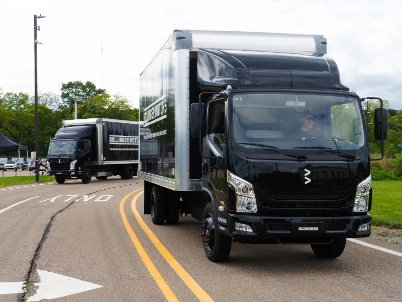 Two black-cab box trucks driving toward the camera.