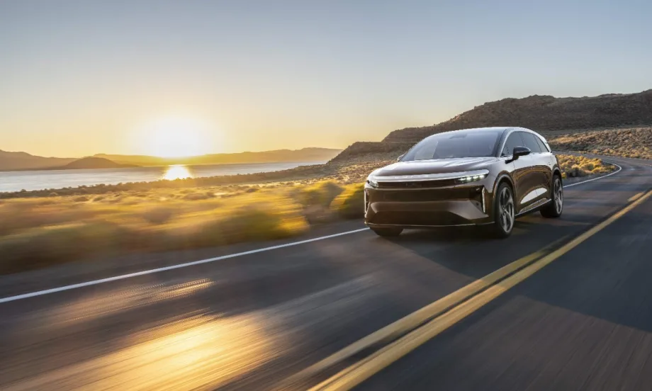 Lucid Gravity electric SUV driving on an open highway at sunset, showcasing the vehicle equipped with advanced navigation and positioning technology.