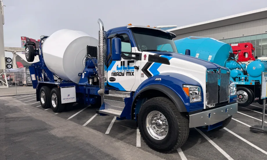 Photo of a concrete truck parked, blue and white cab, white mixer.