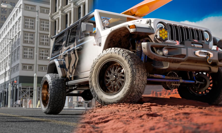 Low-angle photo of a Jeep with aggressive off-road tires parked on top of a dirt mound.