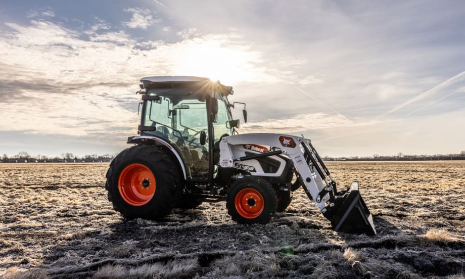 Bobcat tractor with front bucket parked in a field.