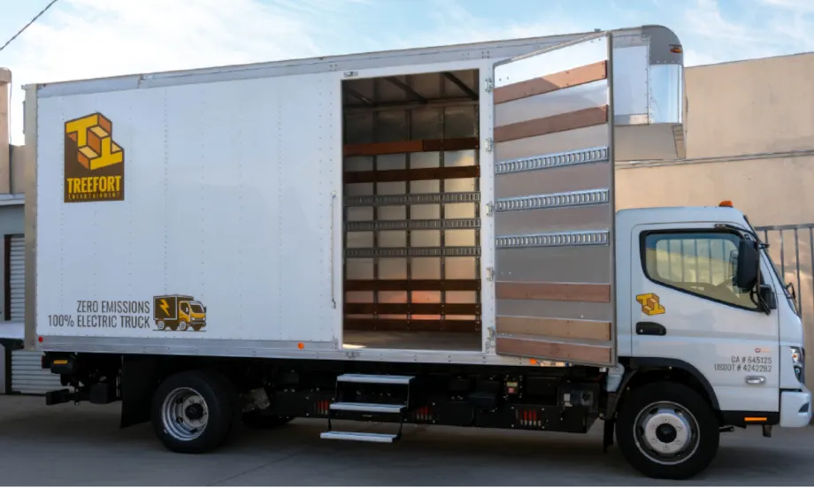 Medium-duty battery-electric box truck parked with side door open.