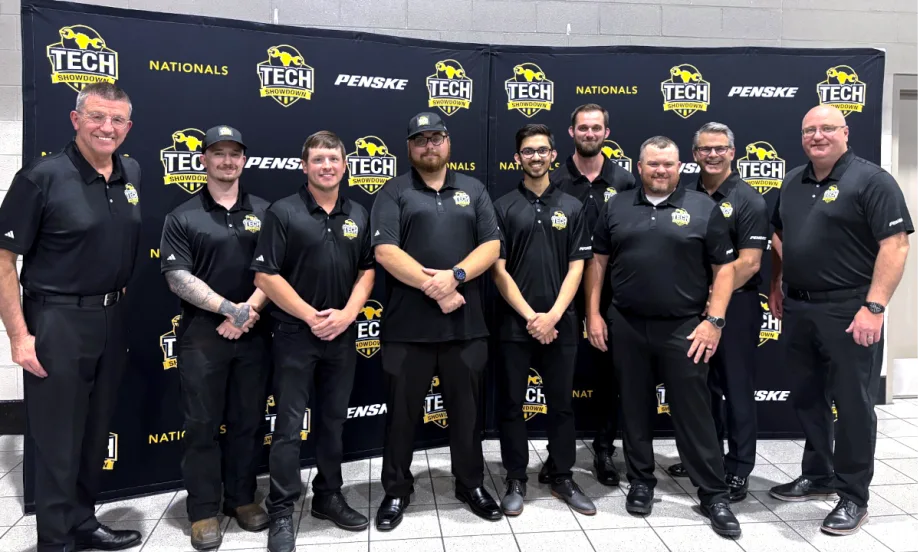 Group of men, award winners in a competition, dressed in all black standing on a stage to receive awards.