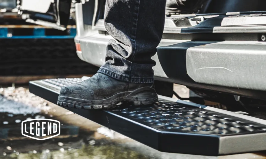 Work boot stepping onto Legend FixStep rear step with anti-slip steel tread in wet outdoor conditions, showcasing traction and durability.