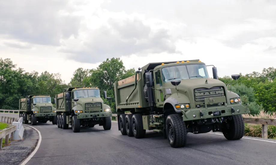 Three military dump trucks driving on a test track.