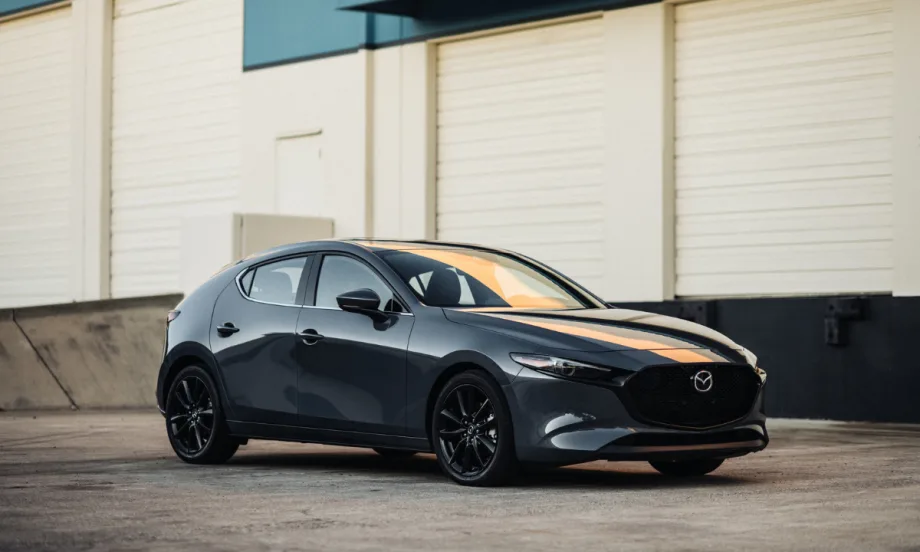 2026 Mazda3 hatchback in gray parked outside an industrial building.