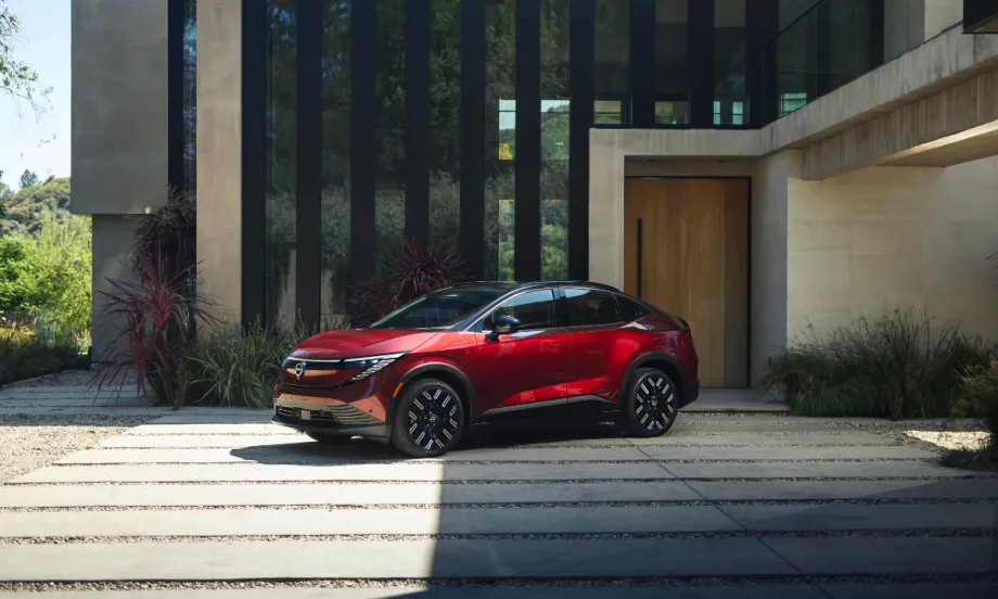 A red 2026 Nissan LEAF parked in front of a modern home.
