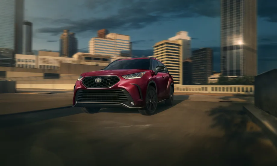 Red Toyota SUV driving through urban cityscape at sunset.