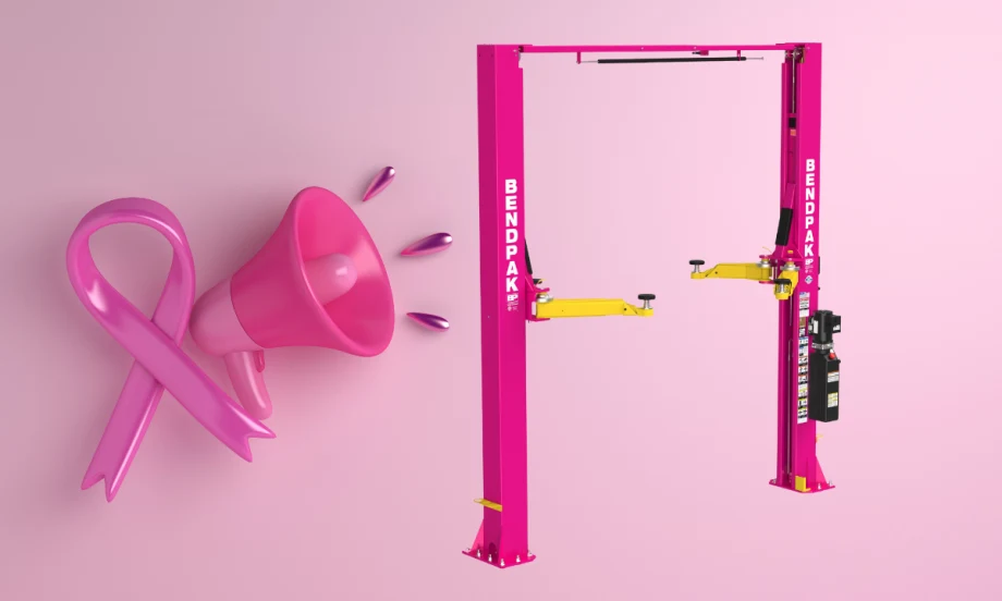 Pink BendPak two-post car lift with yellow arms, shown alongside a pink ribbon and megaphone symbolizing breast cancer awareness.