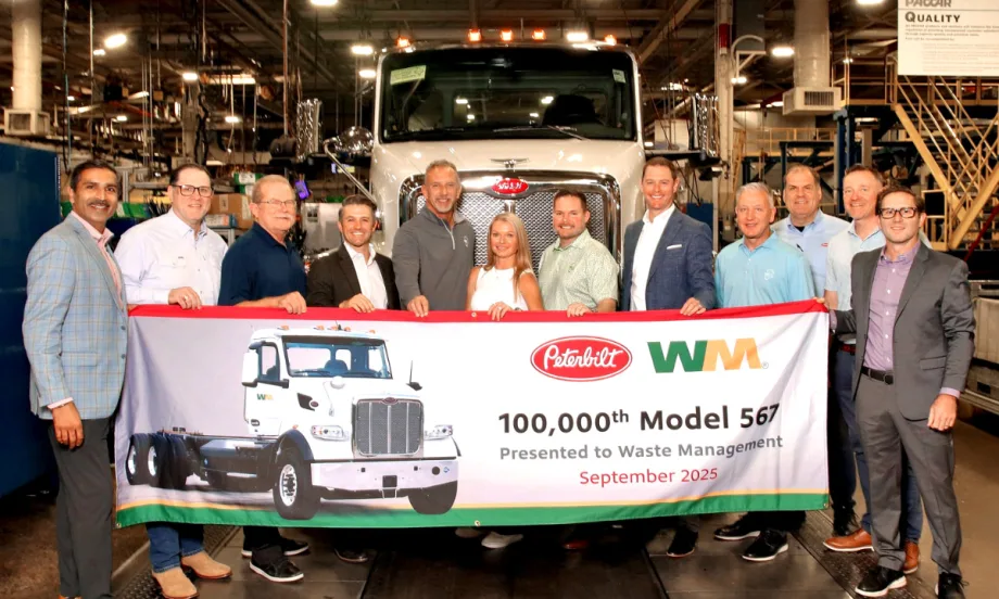 Group of Peterbilt, Waste Management, and Rush Enterprises leaders stand in front of a Peterbilt truck holding a banner celebrating the 100,000th Model 567 delivery in September 2025.