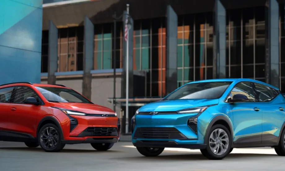 Blue and red 2027 Chevrolet Bolt EVs parked side by side in an urban setting.