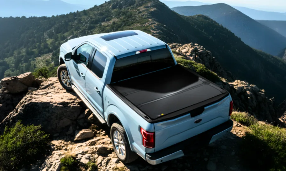Light blue pickup truck with black tonneau cover in a mountain setting.