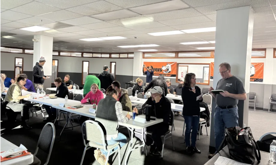 Group[ of people working and talking in a classroom setting.