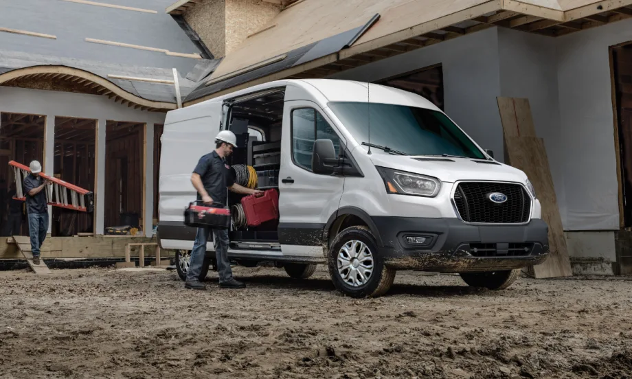 2026 Ford Transit Cargo Van parked at a construction site with a worker loading tools. Photo highlights real world fleet use and new tech updates designed to support daily commercial operations.