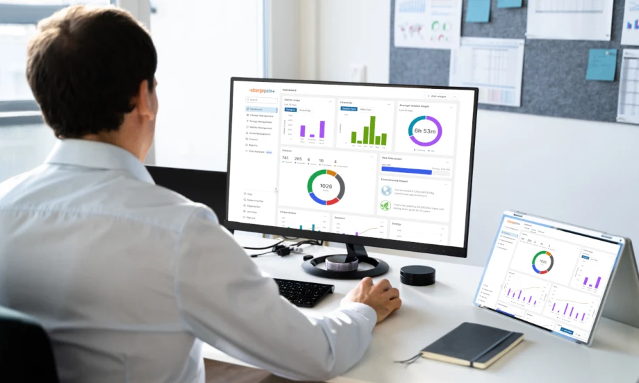 Man seated at desk and looking at charts and graphics on a computer and a tablet.