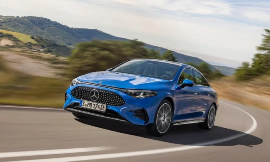 Blue Mercedes-Benz sedan driving on a curving road with blurred hills in the background.