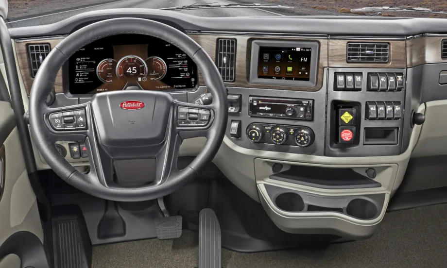 Inside view of a truck cab looking forward at the steering wheel and dash.