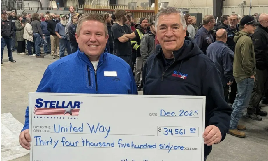Photo or one man presenting a large check to another man with people in the background.