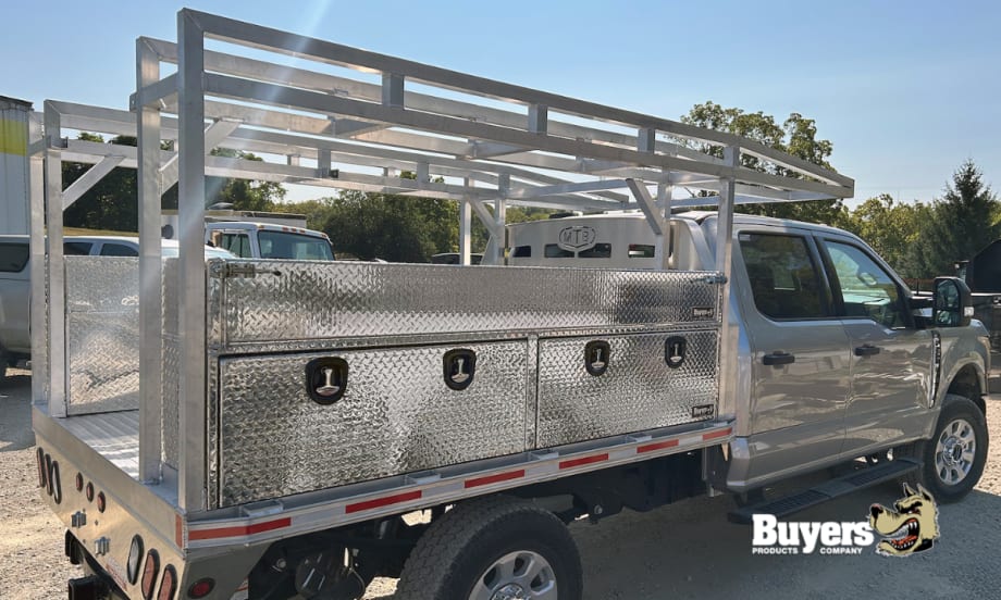 Side view of a work truck with multiple tool boxes and storage bins and a ladder rack on top.