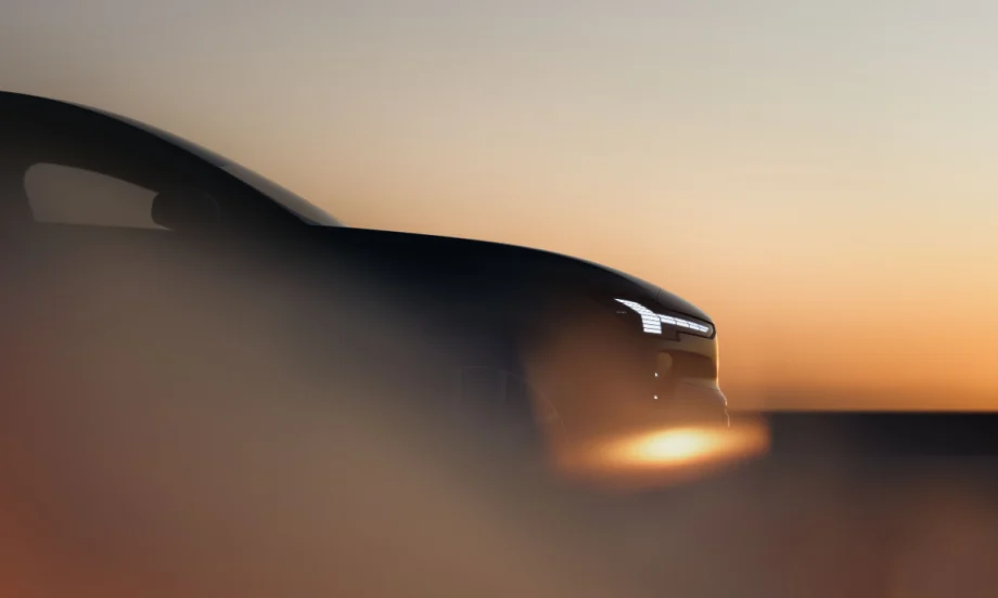 A dark, stylized side view of a vehicle at sunset, with headlights visible.