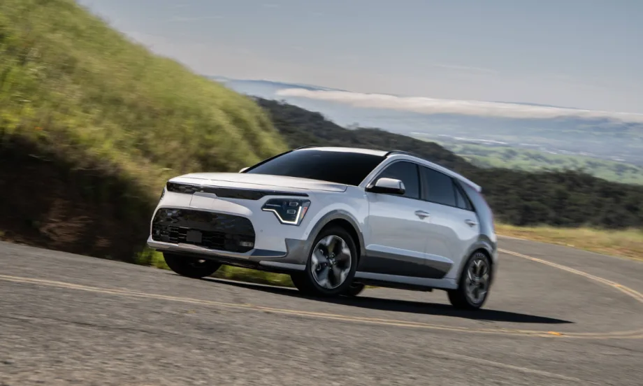 2026 Kia Niro EV driving on a winding road through a hilly landscape.