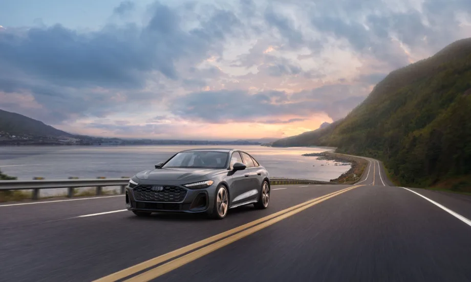 A 2026 Audi A5 driving on a highway near water and hills.