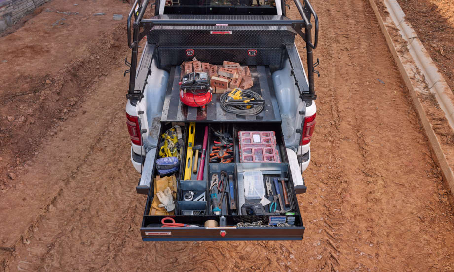 overhead photo of a truck bed tool storage drawer extended on a dirt job site.