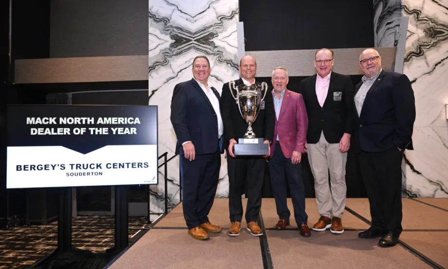 Group of four men and one woman accepting an award on stages.