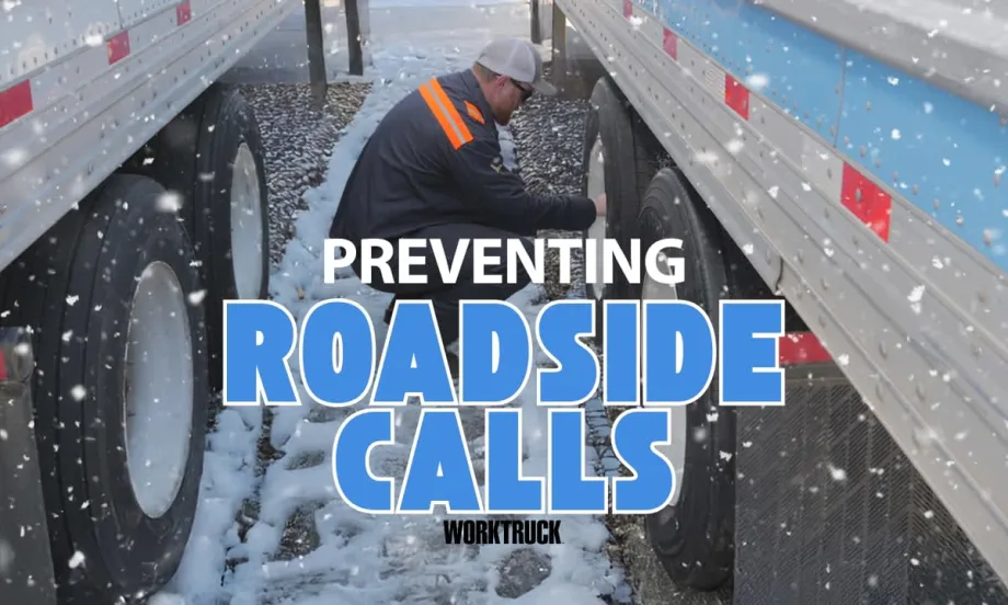 Technician checks semi-truck tire pressure in snowy yard between trailers to help prevent winter breakdowns and roadside calls.