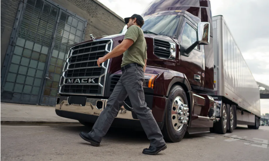 Man walks across in front of a Mack tractor trailer.