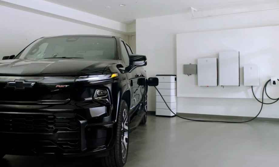 Chevrolet Silverado EV plugged into a home energy system with wall-mounted battery and power management units in a residential garage.