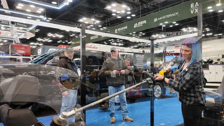Demonstration at a trade show showing a person using a weed whacker against a protected truck seat to test Tiger Tough durability.