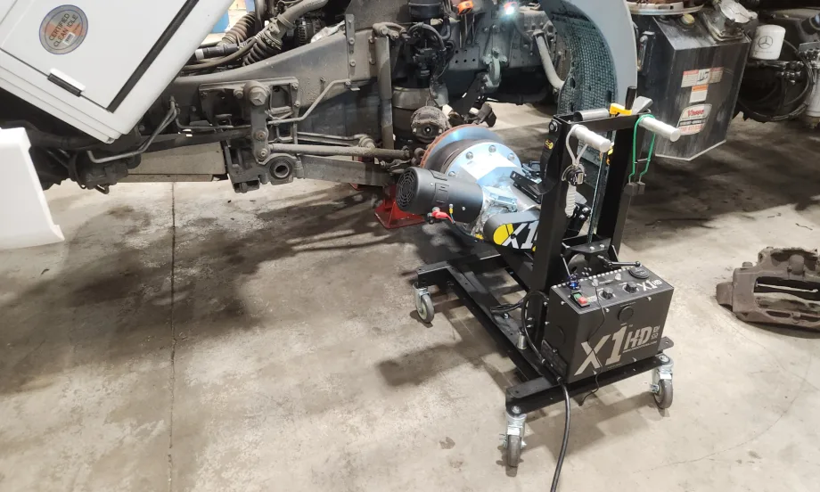 A brake lathe is attached to a truck wheel in a repair shop.