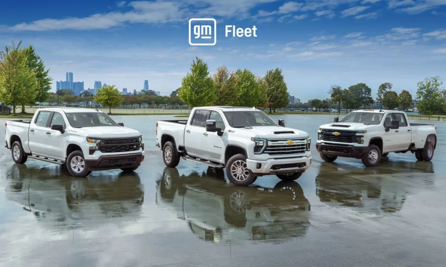 Three white pickup trucks parked in a parking lot with trees in background and a blue sky with logo for GM Fleet.