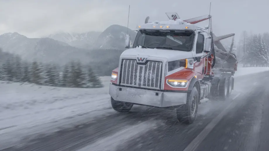 Western Star truck hauling logs through a snowy mountain road during a winter storm, highlighting extreme cold durability and performance testing.
