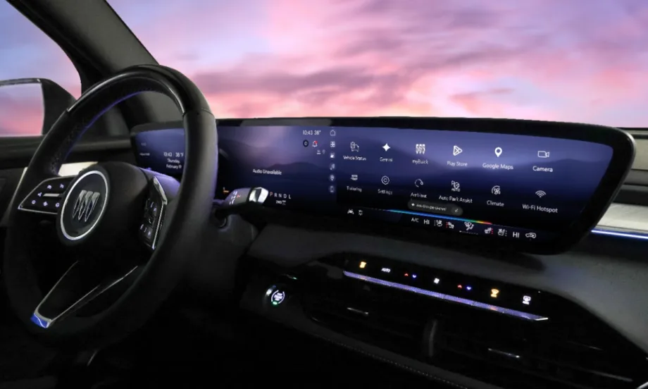 View of a GM vehicle dash with a large infotainment screen and purple sky viewed through windshield.