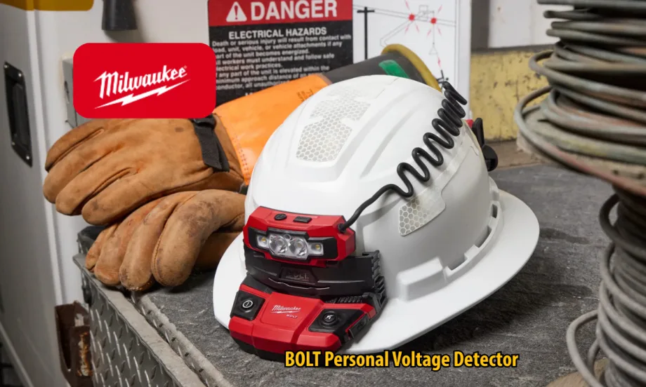 Milwaukee BOLT Personal Voltage Detector mounted on a white hard hat beside work gloves and electrical hazard signage. The safety device features integrated lights and a coiled cable in an industrial work environment.