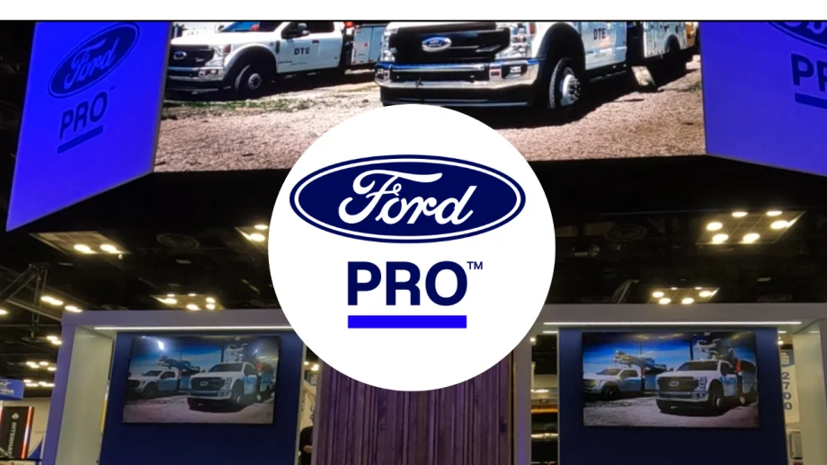 Ford Pro logo over a trade show booth displaying Ford commercial trucks on large digital screens, illustrating the company's commercial vehicle and fleet services showcased at an industry event.