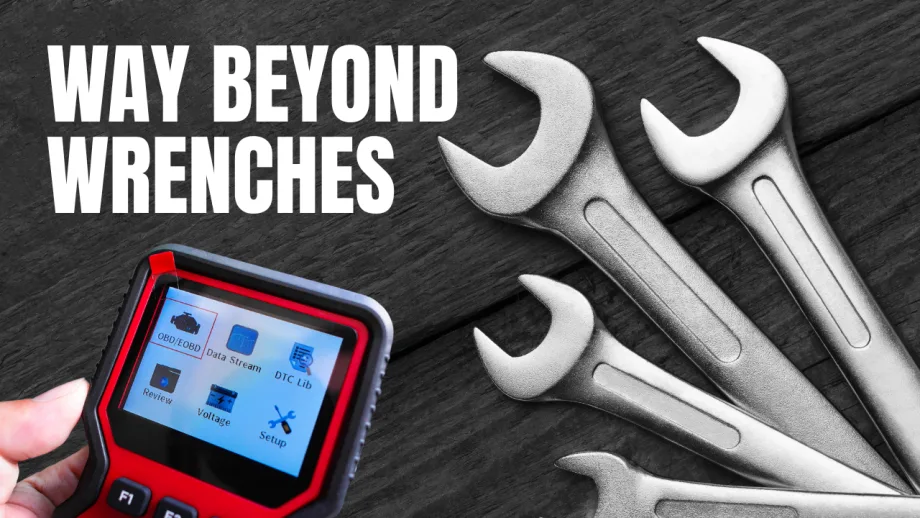 A handheld vehicle diagnostic scanner beside several wrenches on a dark wood surface, with the words “Way Beyond Wrenches” in large white text.