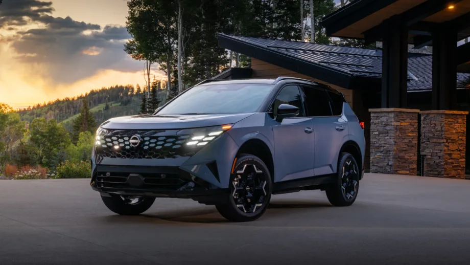 Blue 2027 Nissan Rogue Hybrid parked outside a modern home at sunset, shown from the front three-quarter angle.
