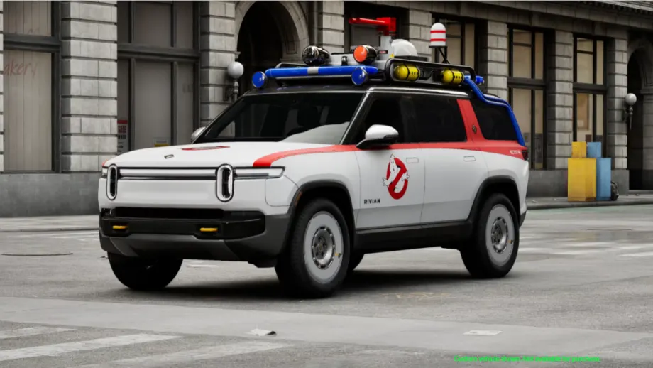 White Rivian R1S SUV customized as the Ghostbusters Ecto-R1, featuring the Ghostbusters logo, red accents, roof-mounted equipment, and emergency-style lights.