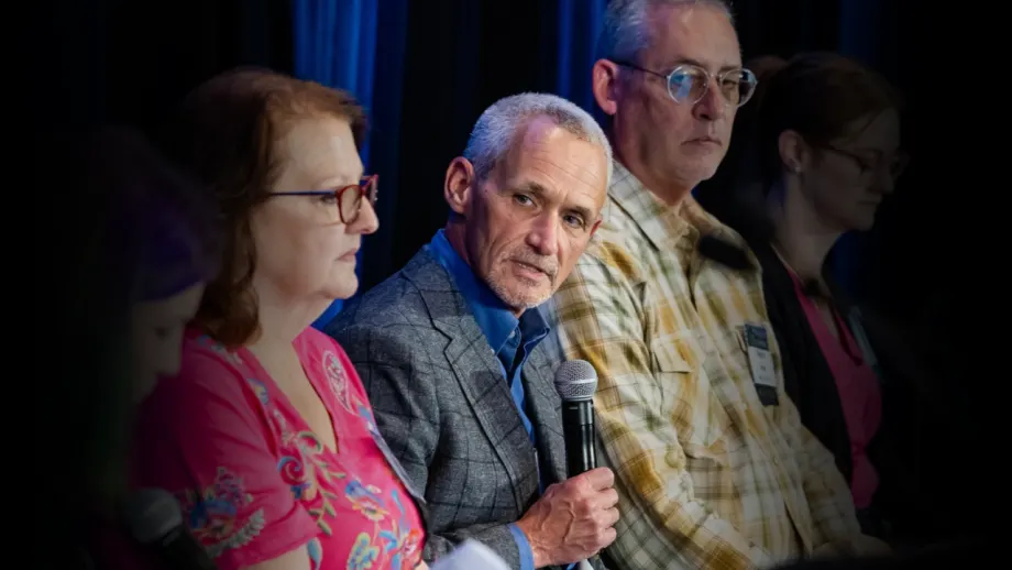 Bob Adamsky, director of fleet management at Arrow International, speaks into a microphone during a panel discussion at Work Truck Exchange, alongside fellow fleet industry professionals.