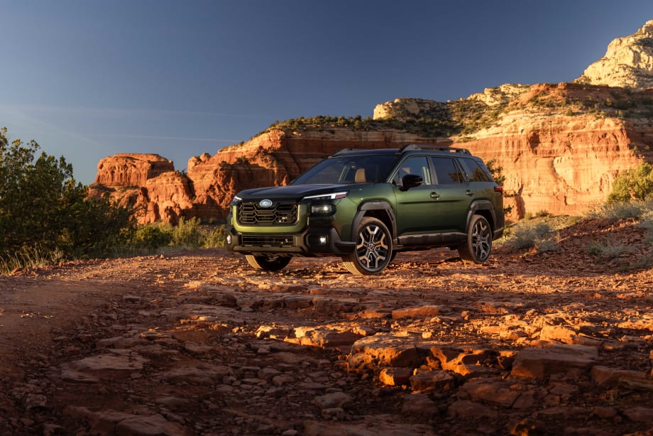 A green 2027 subaru outback drives in the mountains