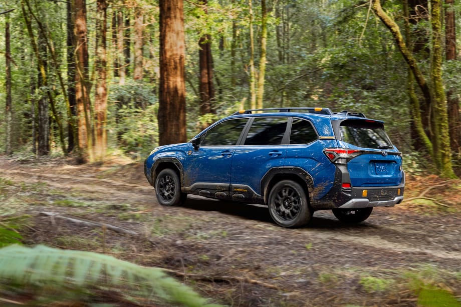 A 2026 BLue FOrester hybrid driving down a dirt road from the rear view