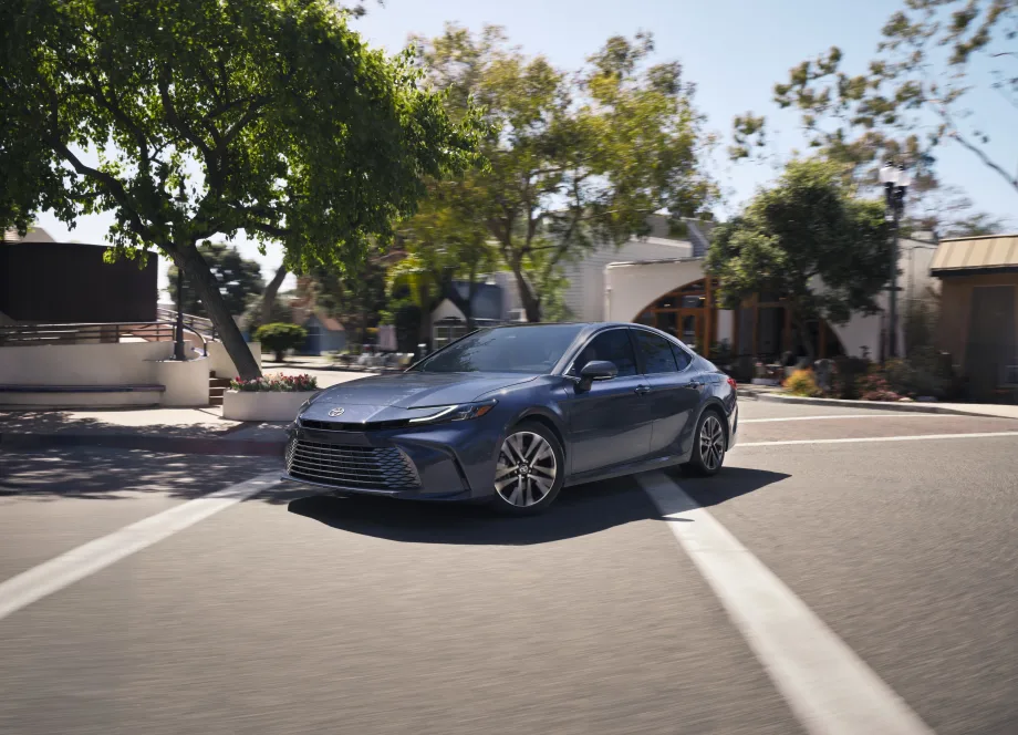 A blue Toyota Camry drives on a road